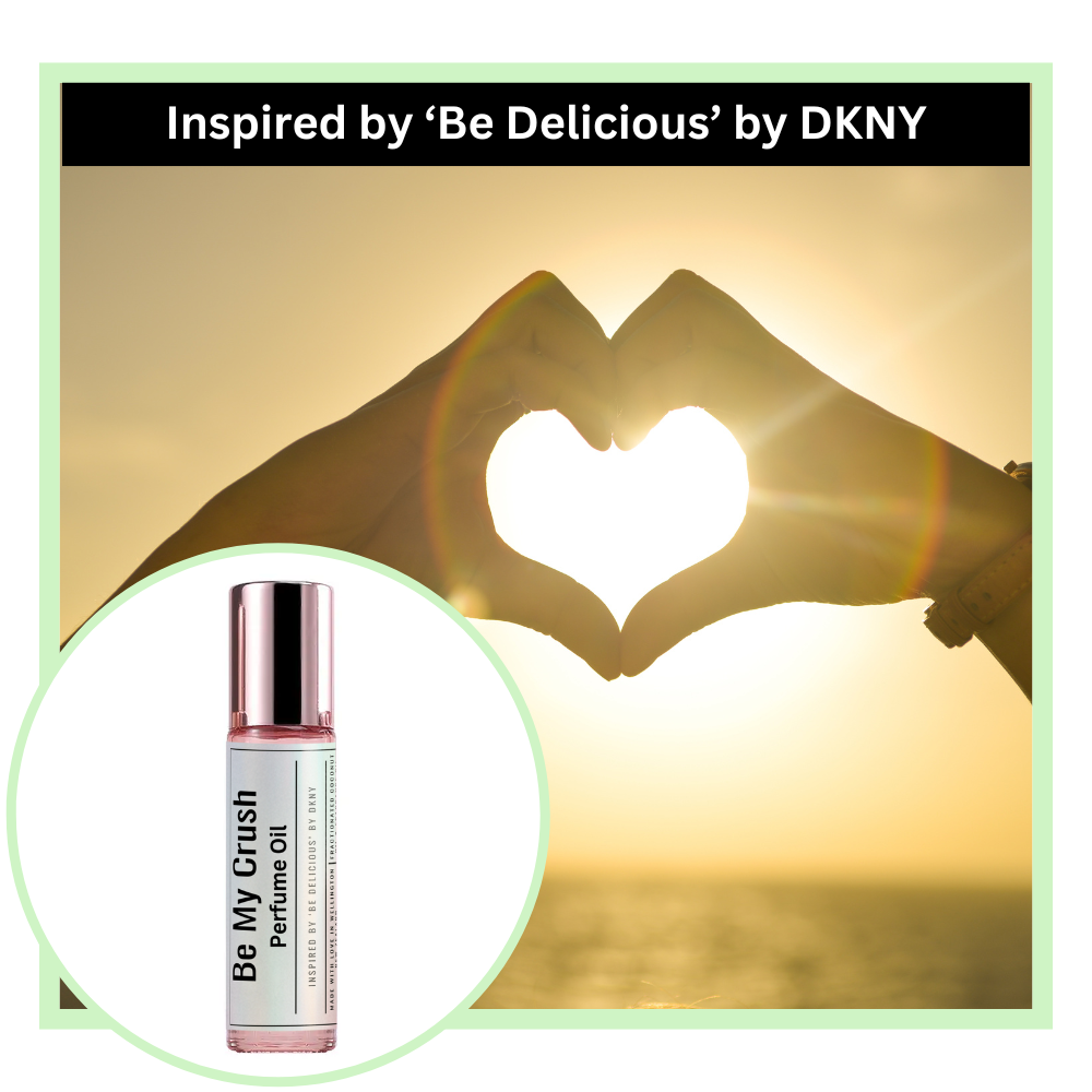 Be My Crush perfume oil bottle with a heart shape created by hands against a sunset background, inspired by 'Be Delicious' by DKNY.