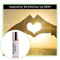 Be My Crush perfume oil bottle with a heart shape created by hands against a sunset background, inspired by 'Be Delicious' by DKNY.