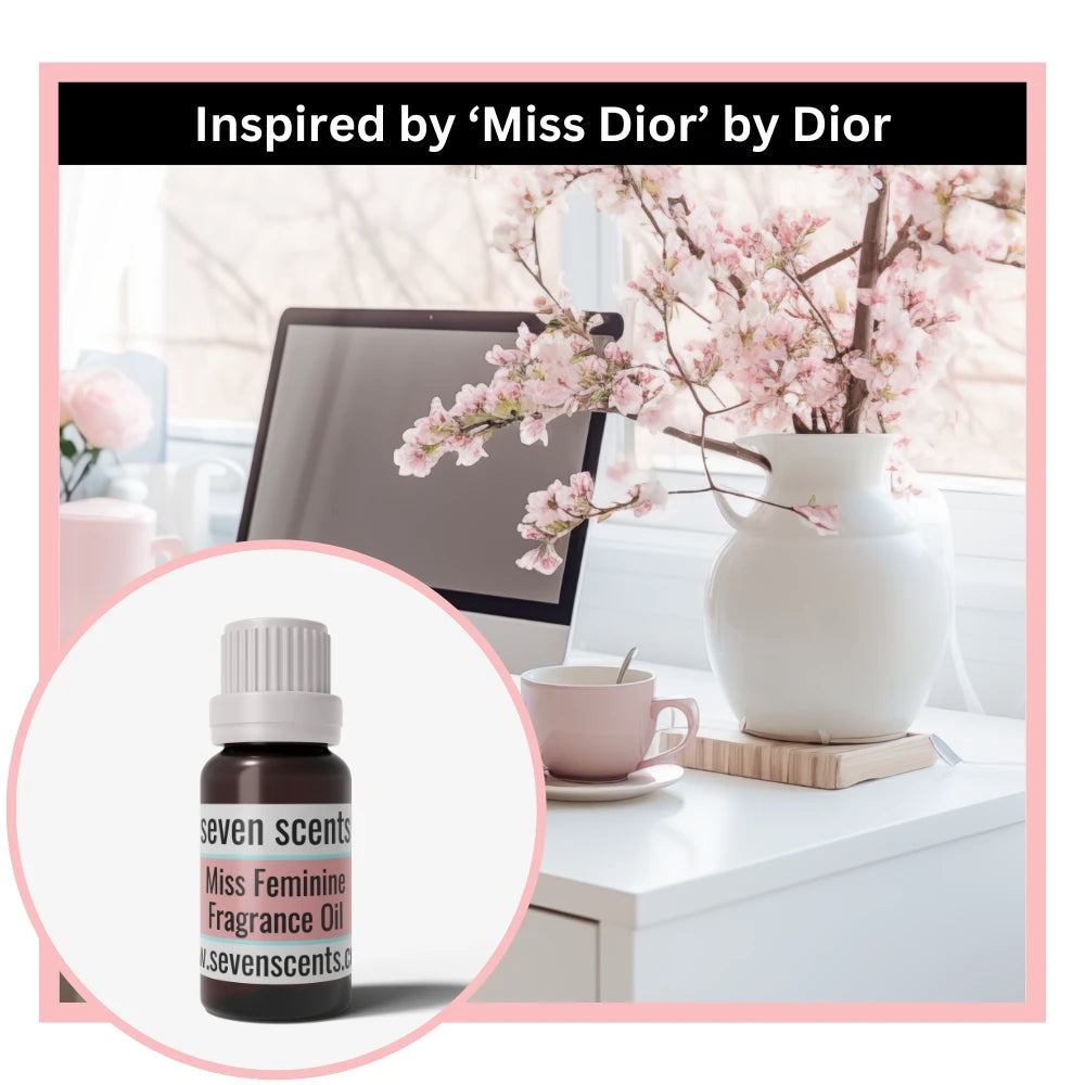 Desk setup with a vase of flowers, computer, and Seven Scents miss feminine fragrance oil inspireed by 'Miss Dior' by Dior.